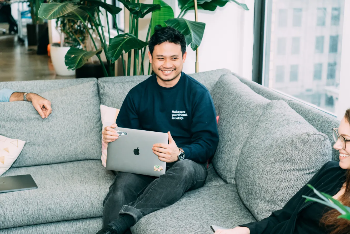 Colleagues smile and chat on couches.