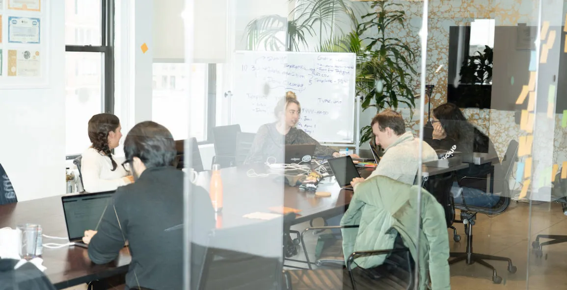 Employees work together at a long table in one of the Enigma conference rooms.